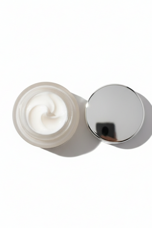 Cream jar with silver lid on a white background