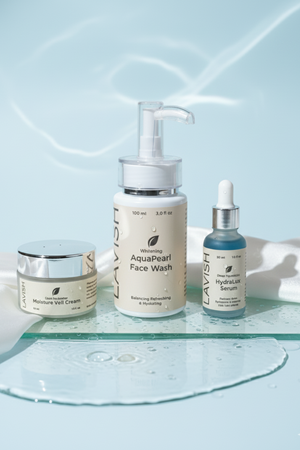 Set of skincare products including a cream, face wash, and serum on a glass tray with a light blue background.