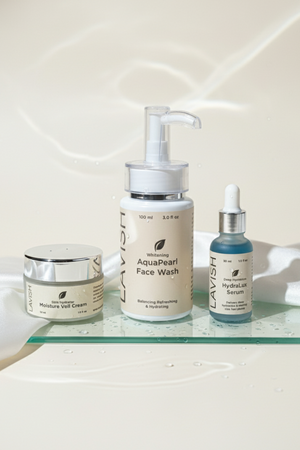 Skincare products including a face wash, cream, and serum on a glass shelf.